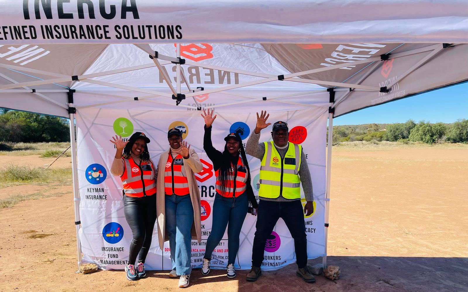 INERCA staff in branded reflective vests under the company gazebo at the school